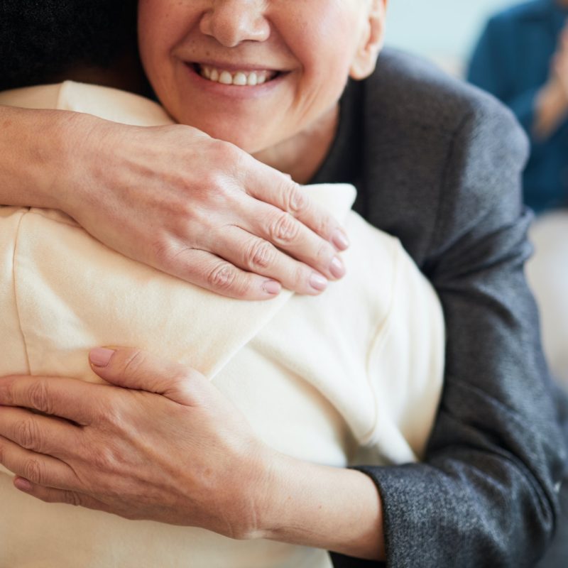 smiling-psychologist-embracing-patient-in-support-group.jpg